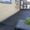 Terrasse i sorte massive komposit terrasse brædder. Højbed på terrasse. sort terrasse til gule mursten. terrasse med bort