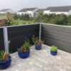 Vedligeholdelsesfrit komposithegn i gråsort med træstruktur. Terrassehegn. Galvaniserede stålstolper og komposit hegnsbrædder