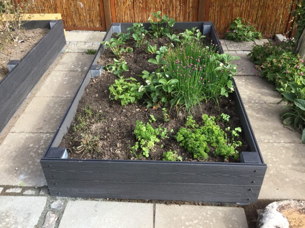 Højbed i massiv vedligeholdelsesfrit komposit. Gråsorte terrassebrædder i komposit monteret på stålstolper.