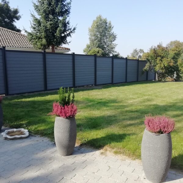 Vedligeholdelsesfrit havehegn. Betongrå komposit brædder med træstruktur og kompositstolper med not. Højt hegn