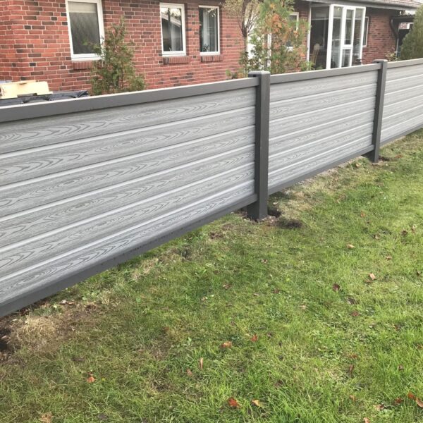 Vedligeholdelsesfrit forhave hegn. Betongrå komposit brædder med træstruktur og kompositstolper med not. Lavt hegn