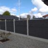 Komposithegn i betonstolper. Gråsort komposite med træstruktur og galvaniserede u-skinner monteret i betonstolper