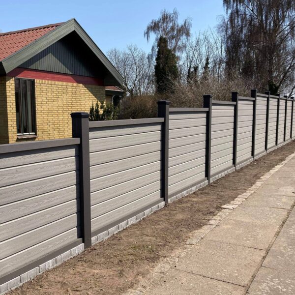 Vedligeholdelsesfrit havehegn. Betongrå komposit med træstruktur og kompositstolper med not. Giver læ ved terrassen