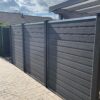 Terrasse hegn i vedligeholdelsesfrit gråsort komposit. Galvaniserede u-skinner og komposit stolper. Giver læ på terrassen