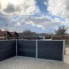 Vedligeholdelsesfrit komposithegn i gråsort med træstruktur. Havehegn. Galvaniserede stålstolper og hegnsbrædder med fer og not