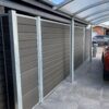 Vedligeholdelsesfrit komposithegn i gråsort med træstruktur. Hegn i carport. Galvaniserede stålstolper og hegnsbrædder med fer og not