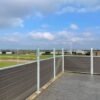 Vedligeholdelsesfrit komposithegn i gråsort med træstruktur. Terrassehegn. Galvaniserede stålstolper og hegnsbrædder med fer og not